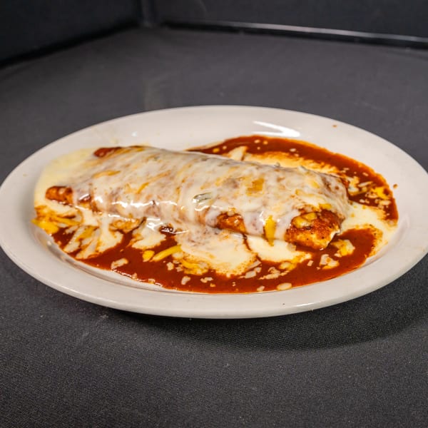 A large, cheesy burrito covered in red sauce and white cheese on a white plate.