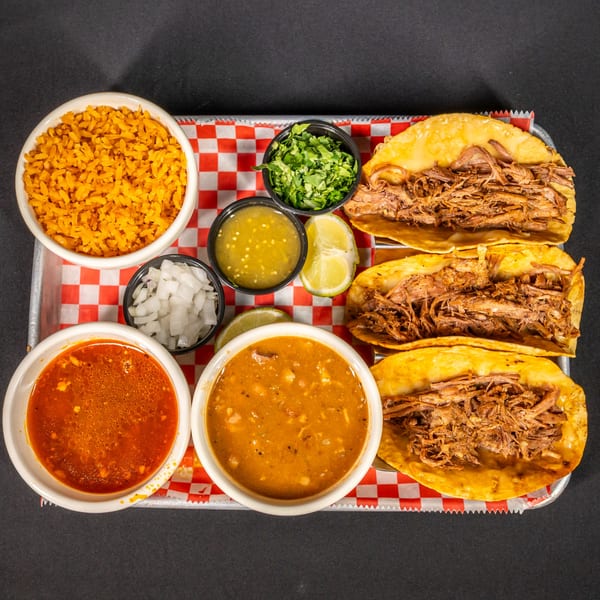 Three El Paso Mexican Grill birria tacos with rice, two soups, salsa, onions, cilantro, and lime.